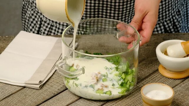 Step-by-step preparation of Bulgarian cold tarator soup with fresh cucumber, dill, natural yogurt or sour milk on a gray wooden background. Bulgarian cuisine. Step-by-step video recipes.