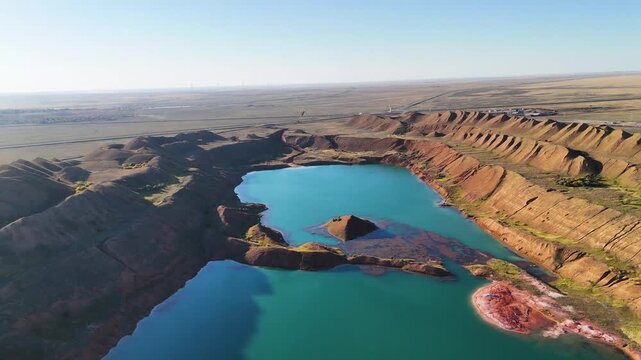 Drone view of turquoise water flooding massive hills of red refractory clay and bauxite ore dumps. A unique technogenic landscape near the city of Arkalyk, Kostanay region. Dramatic color contrast in 