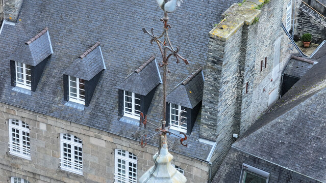 Aerial view of the slate rooftops and weather vane of Eglise Saint-Melaine de Morlaix with stone walls and dormer windows Morlaix, Bretagne, France.