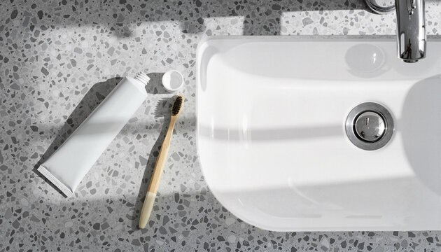 Toothbrush and toothpaste beside sink on terrazzo countertop  