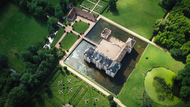 Aerial view of the historic Chateau de Cormatin surrounded by a wide moat and meticulously manicured formal gardens in Cormatin, Bourgogne-Franche-Comte, France.