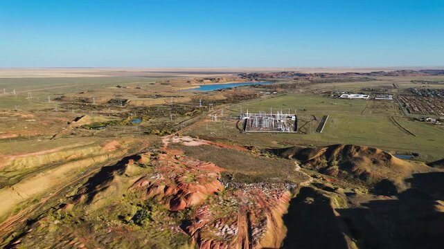Drone view of bauxite ore dumps and red refractory clay hills with electrical power lines and the Arkalyk city skyline in the background. A unique technogenic landscape in the Kostanay region, Kazakhs