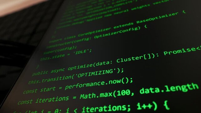 Green lines of JavaScript code scroll across a dark monitor with shallow focus. Concept of backend development, cybersecurity, hacking, and software engineering in a digital world.