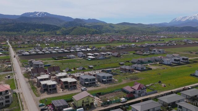 Residential area development and houses under construction with snow capped mountains background, Majestic Aerial Orbit, 4K