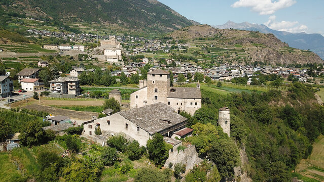 Aerial view of the historic stone castle of Sarriod de la Tour surrounded by lush green trees and vineyards in a mountain valley Aosta Valley, Aosta Valley, Italy.