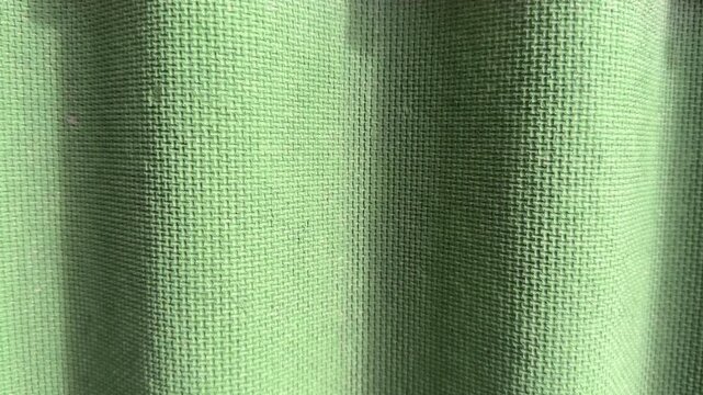 Green corrugated roof tile close-up showing weathered textured surface, subtle moss patches along ridges, sunlight casting soft