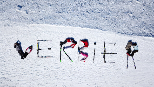 Aerial view of people and skis lying on the snow to spell the word Verbier at the ski resort in Val de Bagnes, Valais, Switzerland.
