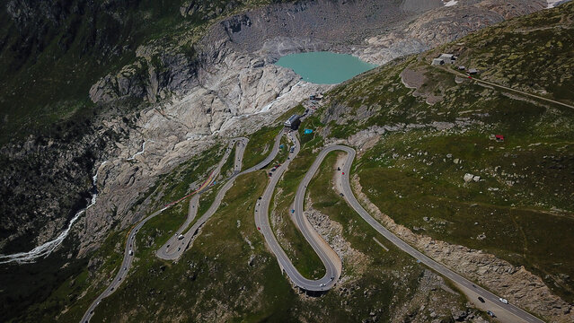 Aerial view of the winding Furka Pass road near the Rhone Glacier lake and rugged alpine peaks in Obergoms, Valais, Switzerland.