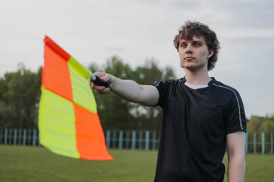 Soccer referee signaling offside with a flag during football match.
