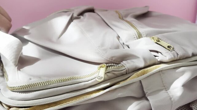 Woman preparing and packing a travel bag for a summer vacation trip, opening the zipper and putting personal items and clothes inside for the upcoming journey and adventure