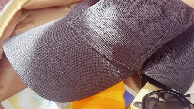 Packing a beach bag with sunscreen, sunglasses, swimsuit, and cap for a sunny summer vacation, showing essential items for a tropical holiday trip and travel preparation