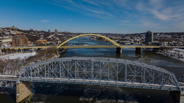 Aerial view of the Big Mac Bridge and Taylor Southgate Bridge spanning the Ohio River with ice floes and snow-covered banks in Cincinnati, Ohio, United States.