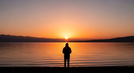 Obraz premium Man watching serene sunset over water.