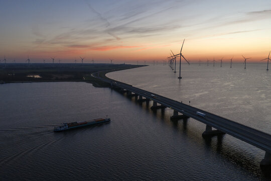 Aerial view of the Ketelbrug bridge and wind turbines at sunset with a barge on the water Nagele, Flevoland, Netherlands.