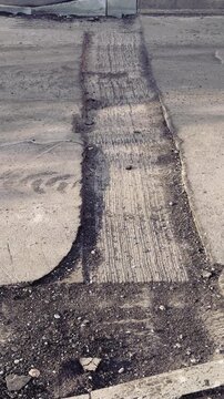 Spring highway pothole preparation empty asphalt, milled edge and loose gravel along curb under soft spring sunlight close-up