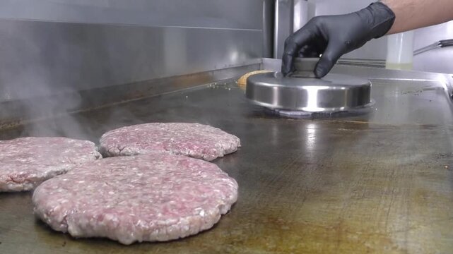 Preparazione di un panino hamburger su piastra. Panino hamburger grigliato con pancetta, cipolla glassata, formaggio e uova