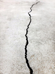 Fototapeta premium Gray cement floor texture with a vertical crack in perspective in the middle, vertical photo.