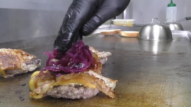 Preparazione di un panino hamburger su piastra. Panino hamburger grigliato con pancetta, cipolla glassata, formaggio e uova