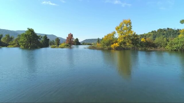 4K calm lake surrounded by autumn trees reflecting colorful nature scenery.