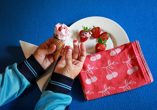 Helado derretido y dedos sucios, pringados manchados pegajosos de fresa fruit strawberry ice cream y nata dulce cream con plato con fruta y trapo para chupar los dedos 