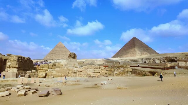 Stunning panoramic view of the great sphinx with the famous pyramids of giza in the background under a blue sky with clouds in cairo, egypt