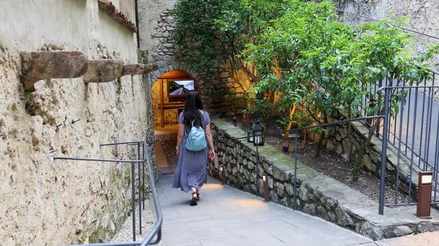 LIMONE SUL GARDA, ITALY - MAY 20, 2025: A female tourist walking through the stone entrance of the historic Limonaia del Castel lemon garden.