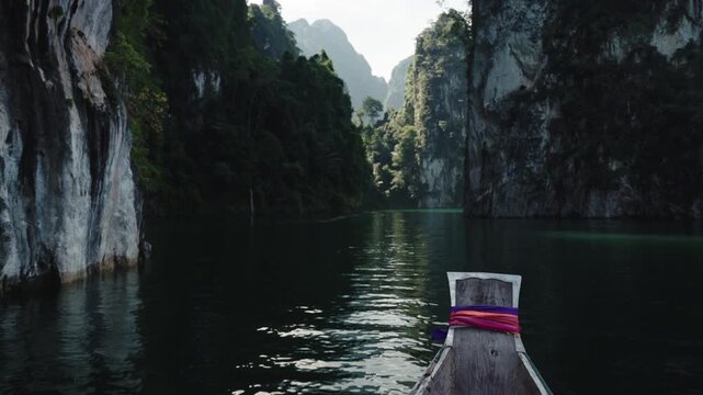 Cinematic Vertical Tilt-Up from Traditional Longtail Boat Prow with Ribbons to Majestic Limestone Mountains and Emerald Lake, Khao Sok National Park, 4k Video