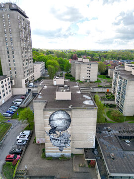 Aerial view of a large steampunk mural on a residential building surrounded by urban architecture and lush green trees Woluwe-Saint-Lambert, Bruxelles, Belgium.