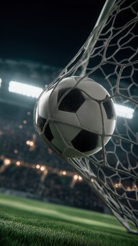 Close view of classic black and white soccer ball caught in goal net on green grass under bright stadium lights during professional night match
