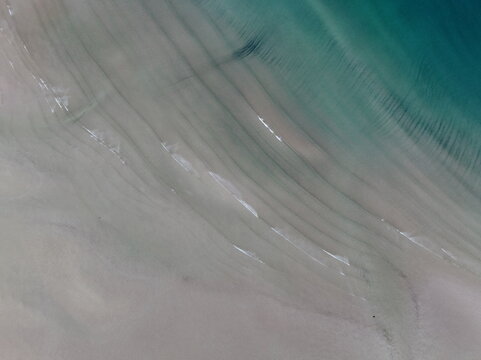 Aerial view of the sandy shoreline of Gruinard Bay with gentle waves and turquoise water ripples Gruinard, Scotland, United Kingdom.