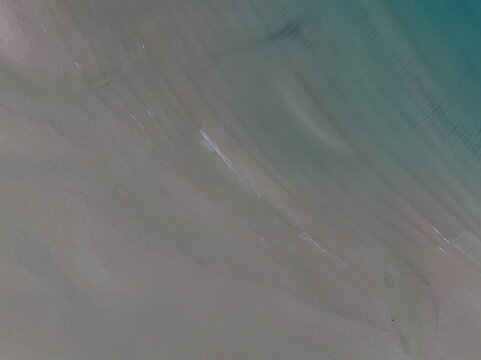 Aerial view of Gruinard Bay featuring sandy textures and turquoise water ripples in Gruinard, Scotland, United Kingdom.