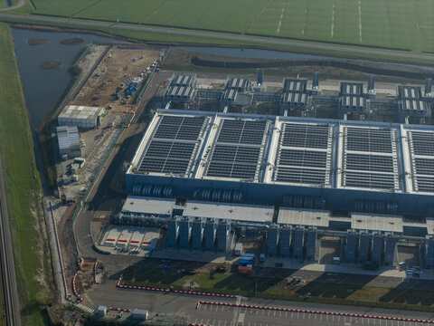 Aerial view of an ai data center with cooling towers and a cloud computing hub exterior near green fields.