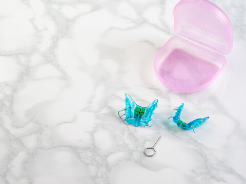 Blue double orthodontic appliance with its pink storage case. Bite correction and pediatric orthodontics.