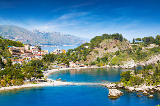 Isola Bella and Mazzaro Bay in Taormina, Sicily at sunny day. Turquoise waters of Mediterranean sea, coastal architecture, lush green hills and pebble beach. Welcome to Taormina concept