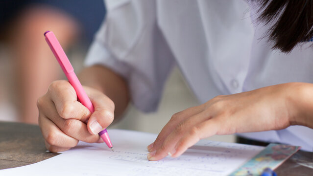 Close up hand of students reading and taking exam sheets exercises answer with stress in classroom