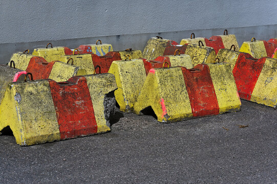 A photograph of weathered yellow and red concrete traffic barriers arranged on an asphalt surface