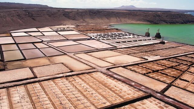 Explore the unique salt pans of Lanzarote. Observe the layout and structure of the salina, with the ocean and landscape in the background