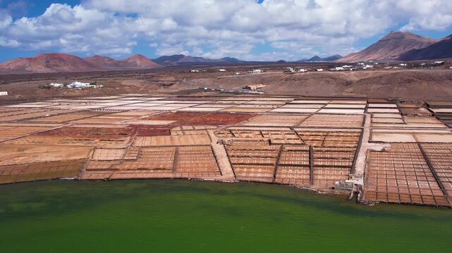 Explore the unique salt pans of Lanzarote. Observe the layout and structure of the salina, with the ocean and landscape in the background
