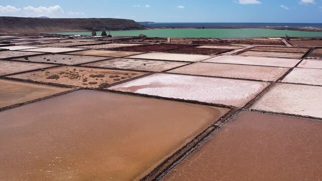 Explore the unique salt pans of Lanzarote. Observe the layout and structure of the salina, with the ocean and landscape in the background
