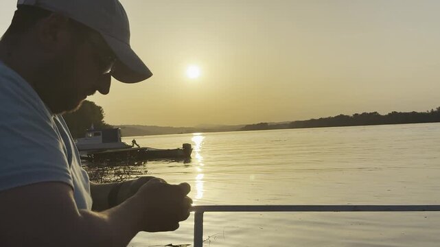 Dramatic silhouette of a fisherman casting a fishing rod on a calm river during sunset twilight. Peaceful outdoor scene with reflective water, fading evening light, and tranquil atmosphere. Perfect fo