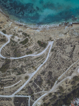 Aerial view of Santuari iber i roma de la Malladeta with winding paths, rocky cliffs, and turquoise Mediterranean waters in La Vila Joiosa, Comunidad Valenciana, Spain.