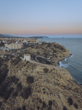 Aerial view of the Santuari iber i roma de la Malladeta on a rugged cliff overlooking the Mediterranean Sea at sunset in La Vila Joiosa, Comunidad Valenciana, Spain.