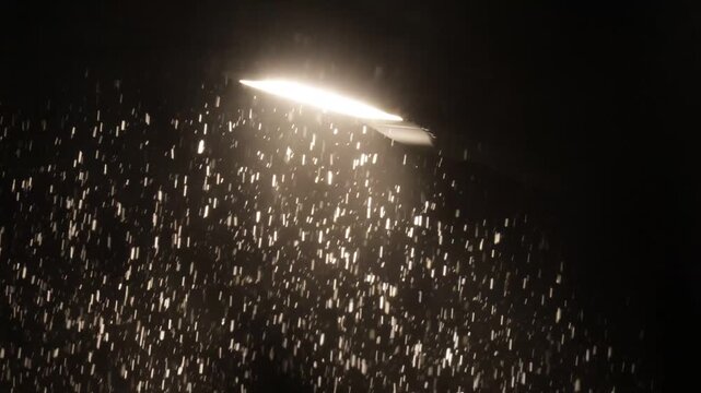 Snowfall against the background of light from a street lamp at night