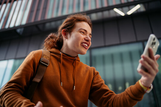 Excited woman looking at smartphone screen with wide smile in urban setting, successful transaction or good news notification on mobile, digital nomad using cellular data roaming service