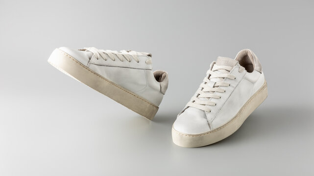 Trendy fashionable grey white leather in dirty grunge style women pair sneakers on neutral background. Casual city style. Summer and spring shoes collection.