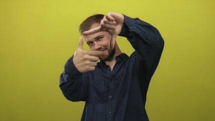Fototapeta premium Young man framing face with hands in studio with lime green backdrop; playfulness creativity imagination.