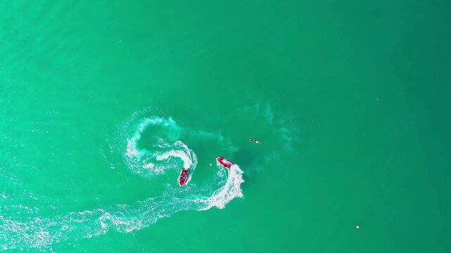 Aerial view of two red jet skis racing on green ocean water