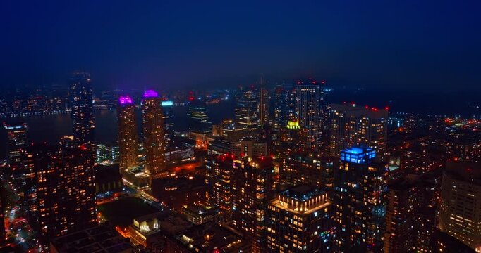 Rising into cloudscape covering the sky over Jersey City, USA. Luminous panorama of the city at night.