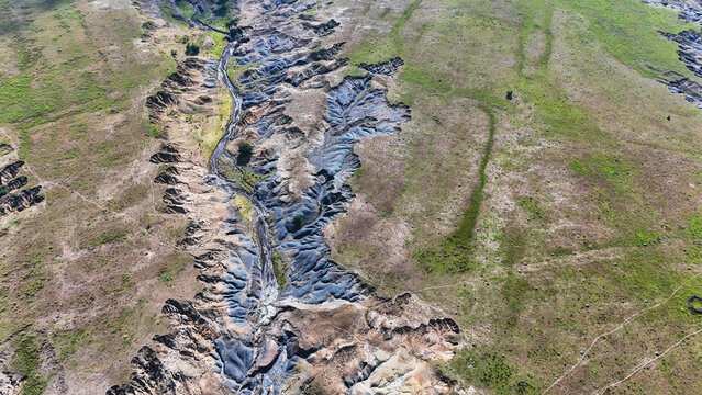 Aerial view of severe soil erosion and deep gullies cutting through the green and brown landscape Pietermaritzburg, KwaZulu-Natal, South Africa.