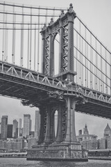 Fototapeta premium Black and white Manhattan Bridge and New York City skyline. Monochrome view of Manhattan Bridge tower and suspension cables with Lower Manhattan skyscrapers in background.